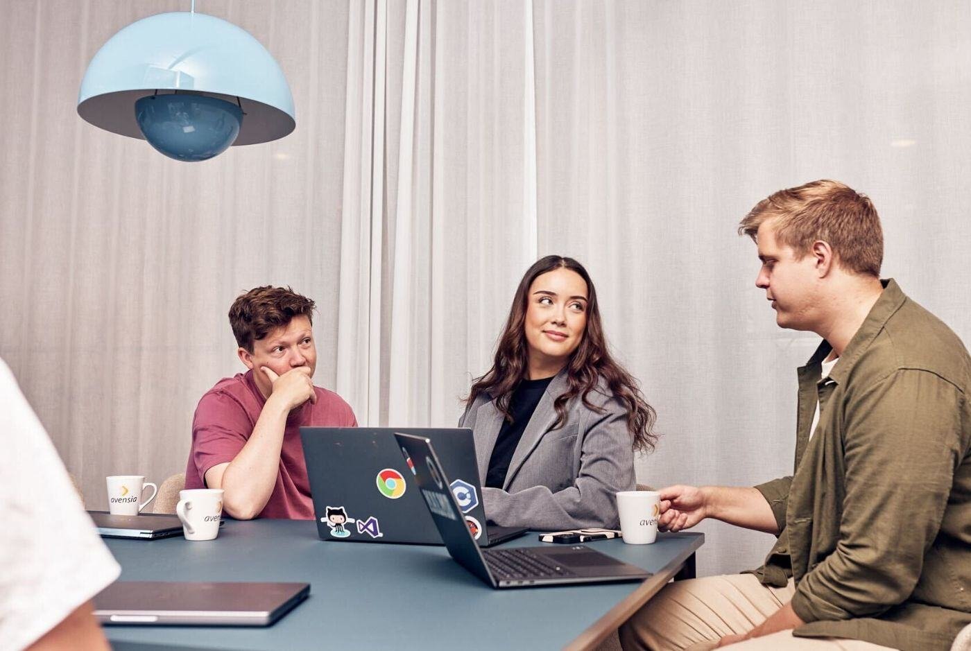 Three colleagues collaborating in a meeting room, focused on a shared task